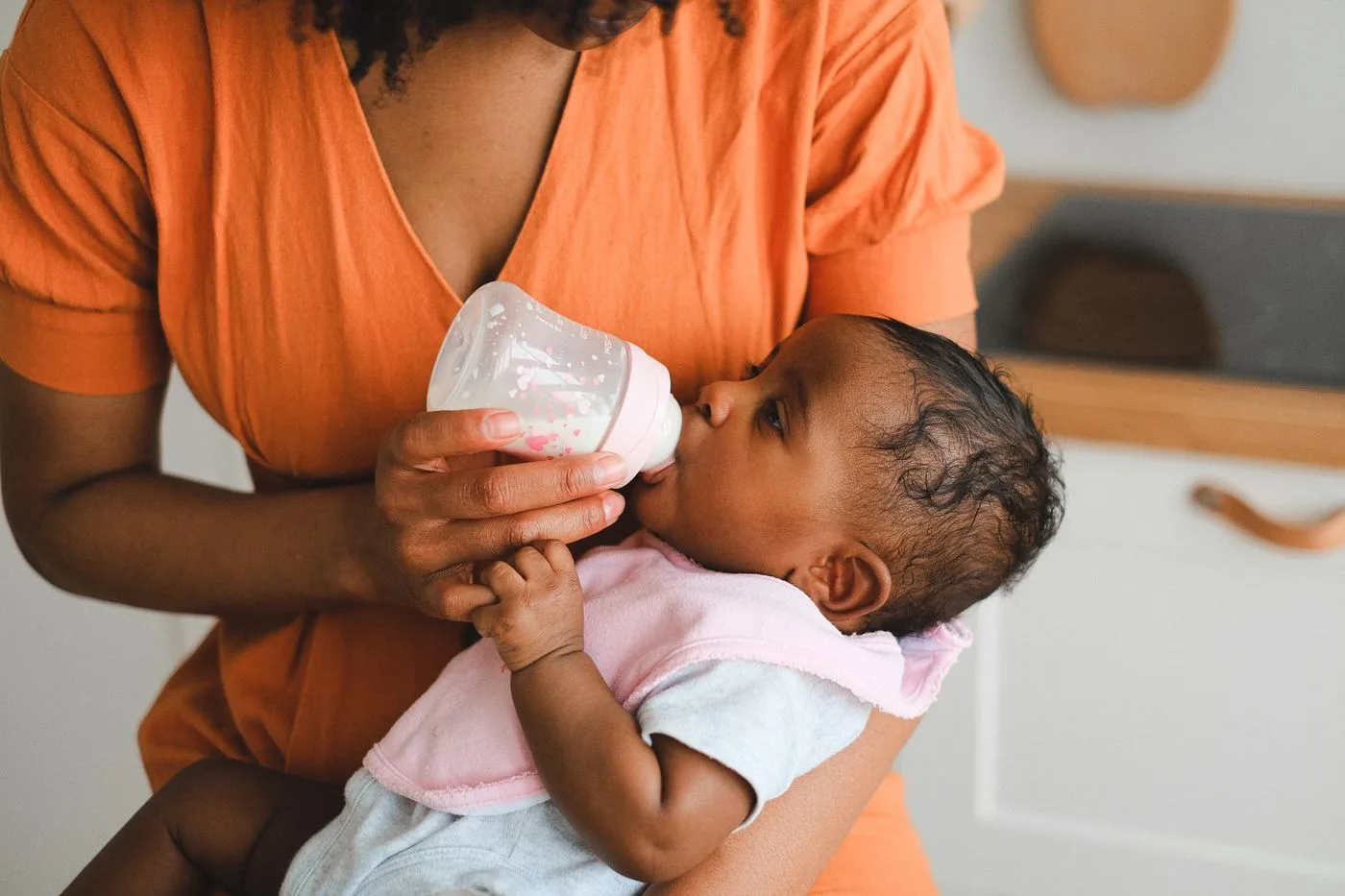 Ein Baby wird im Arm mit einer Flasche gefüttert