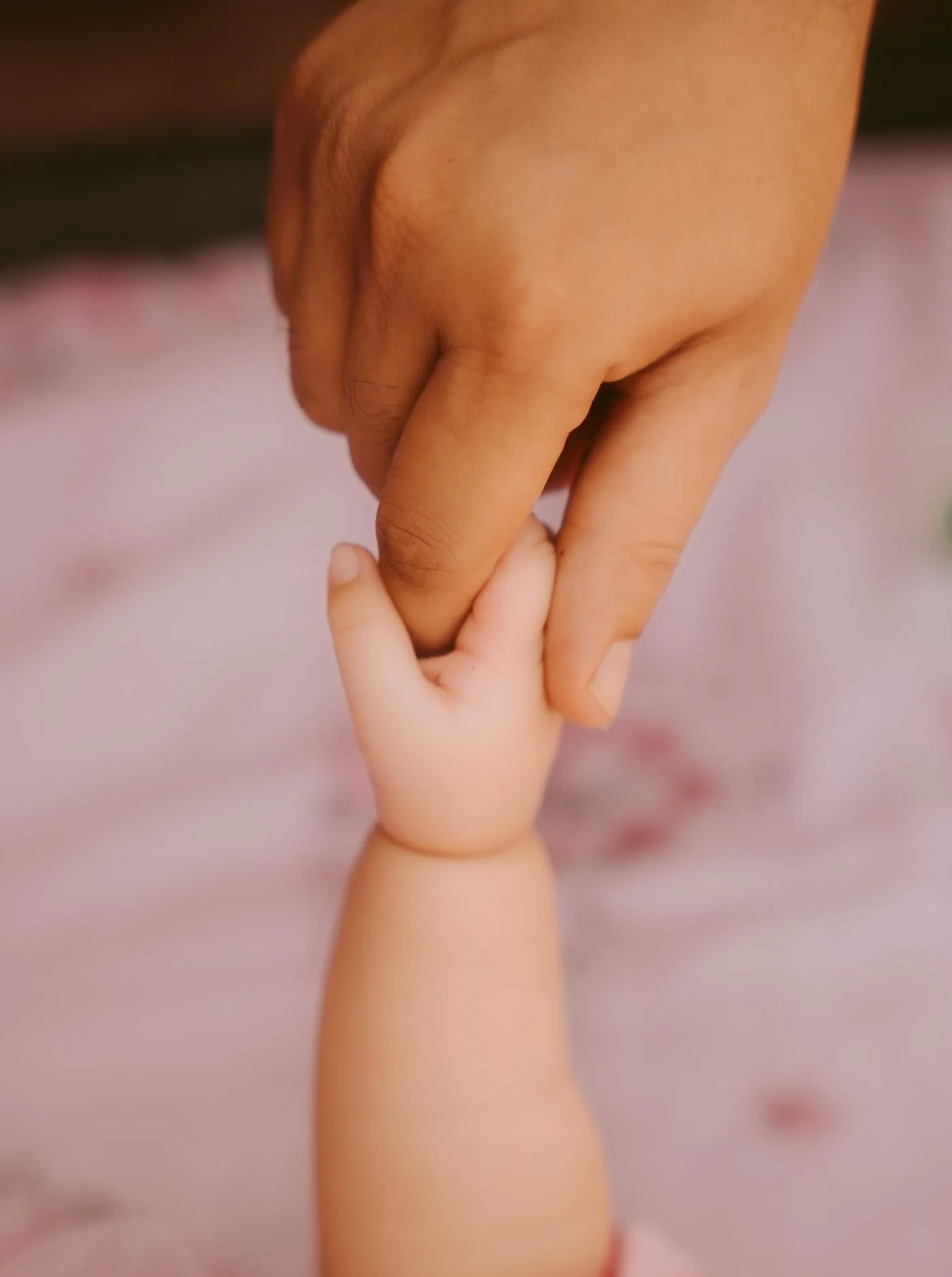 Eine erwachsene Hand hält die Hand eines Babys